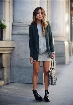 a woman is standing on the sidewalk with her handbag