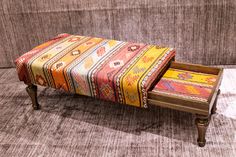 a small bench with a colorful blanket on it's back and footrests