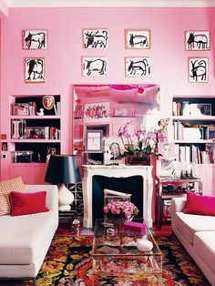 a living room with pink walls and white couches in front of a fire place