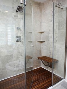 a walk in shower sitting next to a wooden bench on top of a hard wood floor