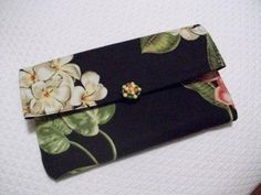 a black and white flowered purse with gold details on the front, sitting on top of a table