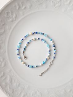 a white plate with a blue and white beaded bracelet on it's side