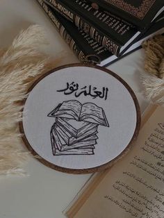 a cross - stitch book with arabic writing on it and some books in the background