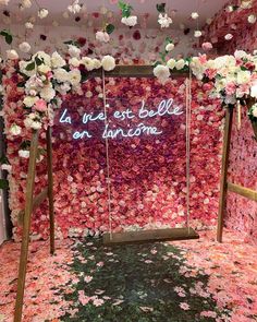 a pink and white flower covered room with flowers on the floor, hanging from ceiling