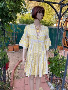 "Pale yellow and white cotton dress, brown stripes. \"V\" neck with one button. 3 tiers, falls bell shape to the knees. Mid length sleeves, ruffled. Tag has been removed, but it's a quality item.  BUST 38\" LENGTH 35.5\" SLEEVES LENGTH  15\"" Floral Embroidery Dress, Vintage Dress 60s, White Long Sleeves, Vintage Dresses 1960s, 1970s Dresses, White Cotton Dress, Mid Length Sleeves, 1960's Dress, Santa Fe Nm