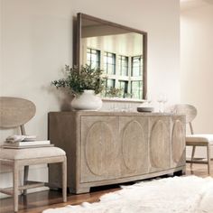 a large mirror sitting above a wooden cabinet in a living room next to a chair