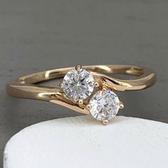 two diamond rings on top of a white piece of rock in front of a gray background