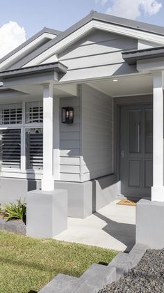 a white house with grey shutters on the front door and windows in the back