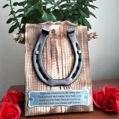 a wooden block with a metal horseshoe on it and flowers in the corner next to it