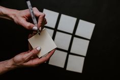 two hands holding a piece of paper with a pen on it and another hand writing something