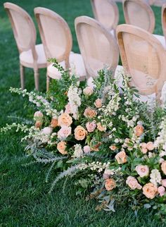 the chairs are lined up with flowers and greenery