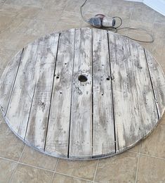 a round wooden table sitting on top of a tiled floor