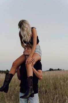 a man carrying a woman on his back in the middle of an open field with tall grass