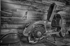 a motor scooter parked in front of a wall with wood planks on it