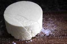 a piece of cheese sitting on top of a wooden cutting board covered in powdered sugar