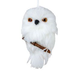 a white owl ornament hanging from a string with a stick in it's mouth