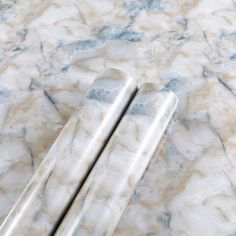 two marbled objects are laying on the floor together, one is silver and the other is white