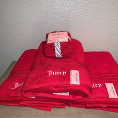 red towels stacked on top of each other in front of a white wall with tags