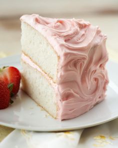 a piece of cake with pink frosting and two strawberries