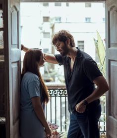 a man and woman standing next to each other in an open doorway looking at each other