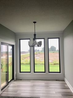 an empty room with three windows and a chandelier