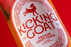 a close up of a bottle of kicking goat soda on a red background with white lettering