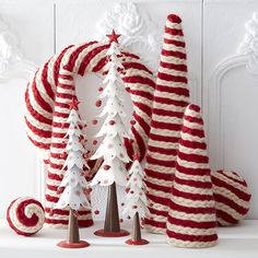 red and white knitted christmas trees on display in front of a fireplace mantel