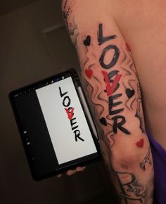 a person holding up a cell phone with the word love on it and hearts painted all over their arm