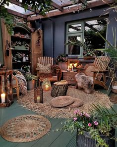 an outdoor area with wicker furniture and candles on the floor, surrounded by potted plants