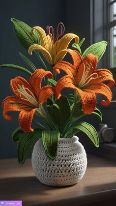 a crocheted vase with orange and yellow flowers in it on a table next to a window