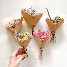 a hand is holding three bouquets with flowers in them and tied to each other