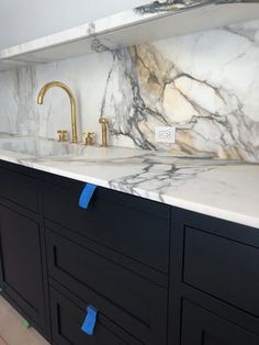 a kitchen with marble counter tops and blue tape on the handles in front of it