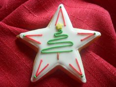 a decorated christmas star on top of a red cloth with green and white icing