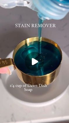 the stain remover is pouring blue liquid into a gold cup on a white plate