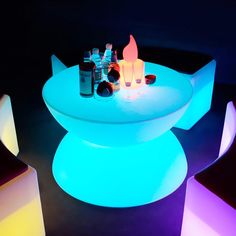 an illuminated table and chairs with bottles on it