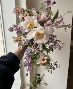 a person holding a bouquet of flowers in front of a window