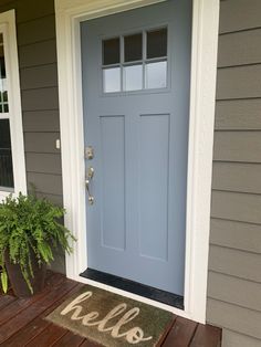 a blue door with the word hello painted on it and potted plants in front