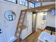 a kitchen with a ladder leading up to the top floor, and a sink below