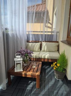 a wooden bench sitting on top of a hard wood floor next to a white curtain