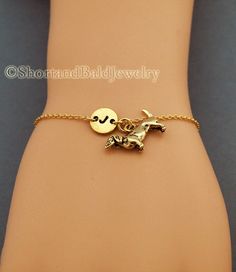 a gold bracelet with a small horse on it's side and a disc charm