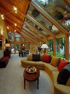 a living room filled with lots of furniture under a glass ceiling covered in light bulbs