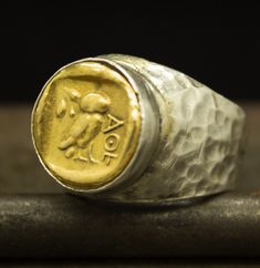 Owl Coin Ring Two Tone Signet Ring Ancient Roman Art 24K Gold Plated 925 Sterling Silver Ring Handcrafted Hammered Jewelry by Pellada Handcrafted hammered full round ring band size measures 1.8 mm in width and 24k gold plated bronze coin 16.4 mm Metal : 925 Sterling Silver Coin : Reproduction Bronze Coin Ring Size : 29.3 x 22.2 mm Coin Bezel Setting Measurements : 16.4 mm Ring Weight : 16.8 grams Ring Size : US 10 (The size you want is made for free). (We used the US standard sizing) **Custom Or Hand Forged Gold Artisan Ring, Handmade Symbolic Gold Signet Ring, Handmade Gold Symbolic Signet Ring, Artisan Gold Ceremonial Rings, Artisan Gold Rings For Ceremonial Occasions, Ceremonial Sterling Silver Engraved Gold Ring, Artisan Gold Ring As Gift, Artisan Gold Rings As Gift, Artisan Gold Rings Perfect As Gifts