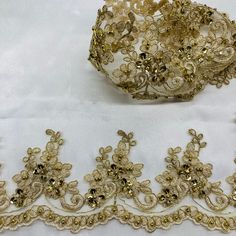 Be mesmerized by the intricate beaded & Corded lace trims featured in our Lace USA line. These luxurious handmade trims bring a touch of elegance and glamour to any look. No matter the occasion, the right trim can make any outfit shine. Choose from our selection of beaded couture lace trims and corded bridal lace trims to make your special day extra sparkly. Whether you prefer corded evening dress lace trim or beaded trim for quinceanera dresses, Lace USA has all your special event needs. For da Beige Lace Fabric With Pearl Embroidery, Beige Pearl Embroidered Lace Fabric, Gold Lace Fabric With Pearl Embroidery, Elegant Embellished Gold Lace, Gold Beaded Lace Embroidered Fabric, Gold Lace Trim For Wedding, Gold Lace With Lace Trim For Wedding, Party Embroidered Lace Trims, Party Lace Embroidered Trims