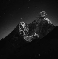 black and white photograph of the top of a mountain at night with stars in the sky