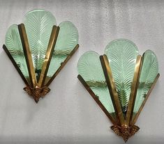 two green glass wall sconces with gold trimmings and leaves on them