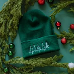 a green knitted hat with christmas decorations around it