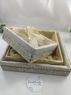 an open box with two pieces of jewelry in it on top of a white table