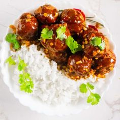 meatballs and rice on a white plate with cilantro garnishes