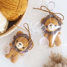 two crocheted teddy bears with tags attached to them sitting next to balls of yarn