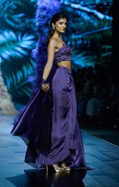 This ensemble features a deep plum embroidered organza corset paired with a luxurious modal satin draped skirt, exuding elegance and sophistication. Completing the look is a delicate glass organza shrug, adding a graceful layer to this stunning outfit—perfect for an effortlessly chic and refined appearance. Luxury Traditional Skirt With Drape, Festive Silk Draped Skirt With Traditional Drape, Purple Organza Pre-draped Saree With Traditional Drape, Voluminous Evening Draped Skirt, Luxury Traditional Draped Skirt, Deep Plum, Draped Skirt, Stunning Outfits, Plum